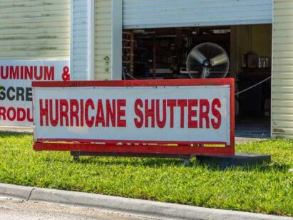 Hurricane Shutters Sign on Grass with a Building in the Background