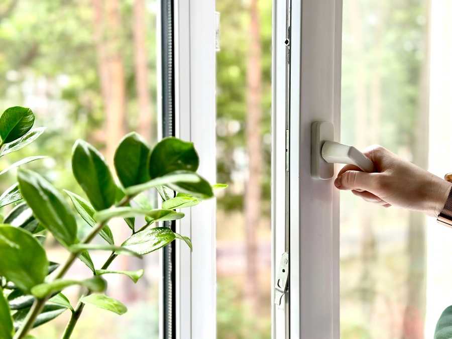 homeowner opening an impact window installed in home